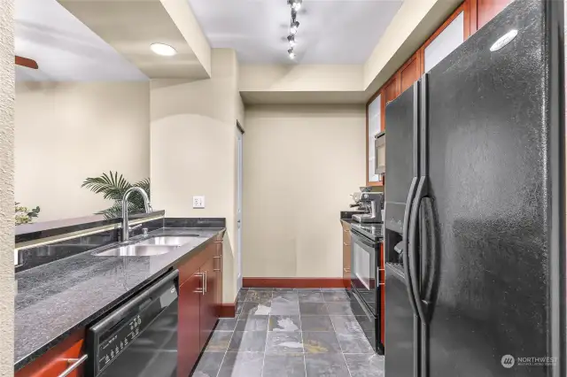 The kitchen has slate floors, black appliances, granite countertops and cherry cabinets.