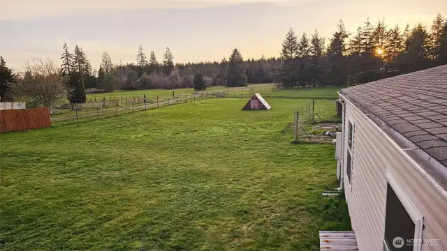 Beautiful sunset view across grassy yards & meadow.