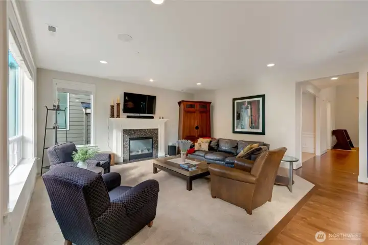 Another angle of the main living area shows the perfect blend of openness and warmth. Plush carpeting meets rich hardwood floors, and the fireplace anchors the space while connecting to the rest of the home’s flowing layout.