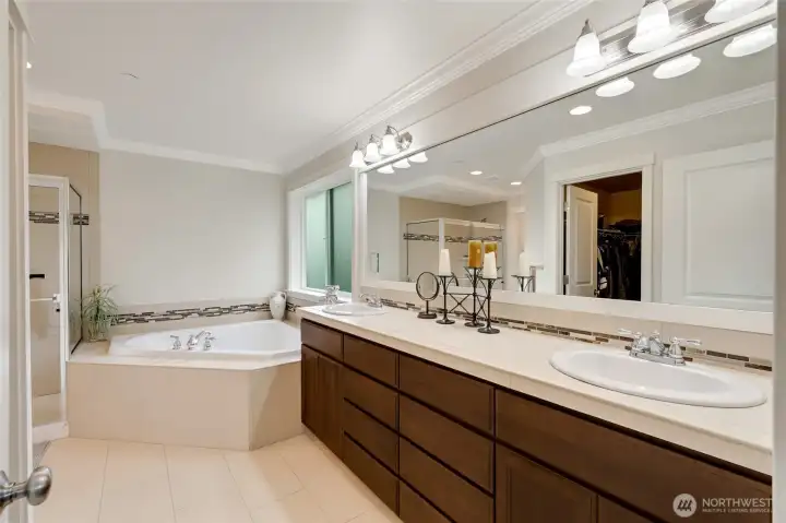 Luxurious five-piece ensuite bath with dual sinks, an oversized vanity, soaking tub, and walk-in shower. Modern tile details and warm cabinetry combine elegance with everyday functionality.