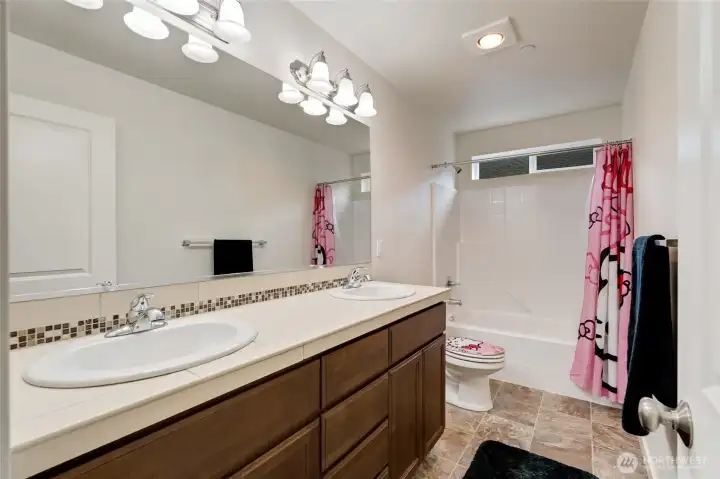 Bright and functional full bath with dual vanities, updated lighting, and tile accents. Perfectly positioned to serve the upper bedrooms, offering plenty of counter space for busy mornings.