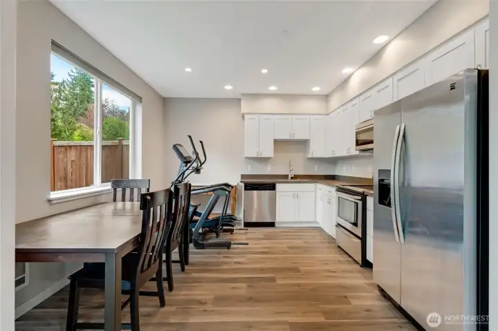 Bright and modern lower-level kitchen with stainless steel appliances, white cabinetry, and durable flooring. Large windows bring in natural light, creating a welcoming space perfect for guests, extended living, or potential ADU use.
