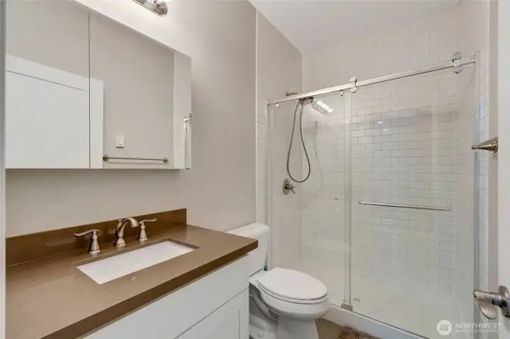 Stylish full bathroom with quartz countertop, subway tile shower surround, and modern fixtures. Designed with a clean, timeless look and located conveniently near the lower bedroom and living area.
