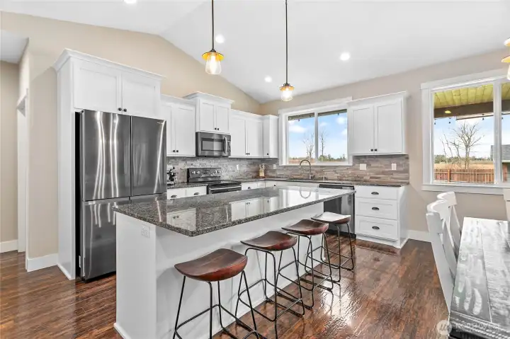 Well-appointed bright kitchen with newer graphite appliances, full height tile backsplash, granite counters & more