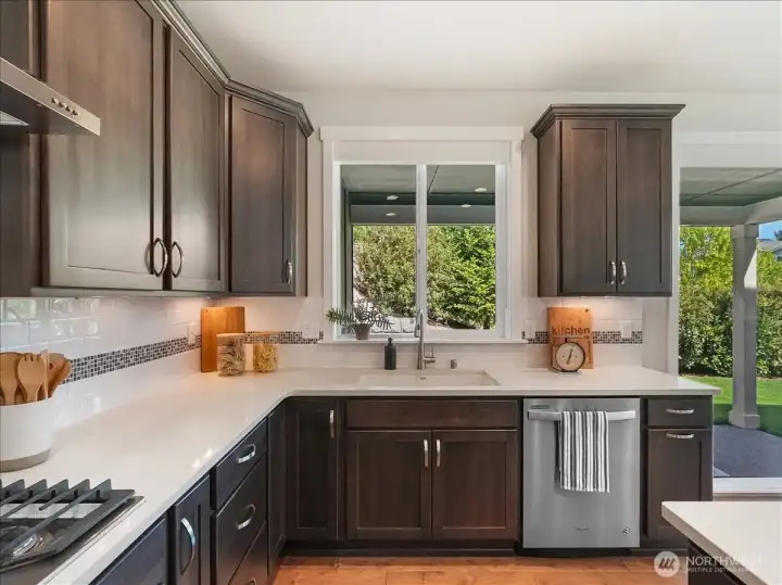 Large picture window frames peaceful views of the beautifully landscaped yard.