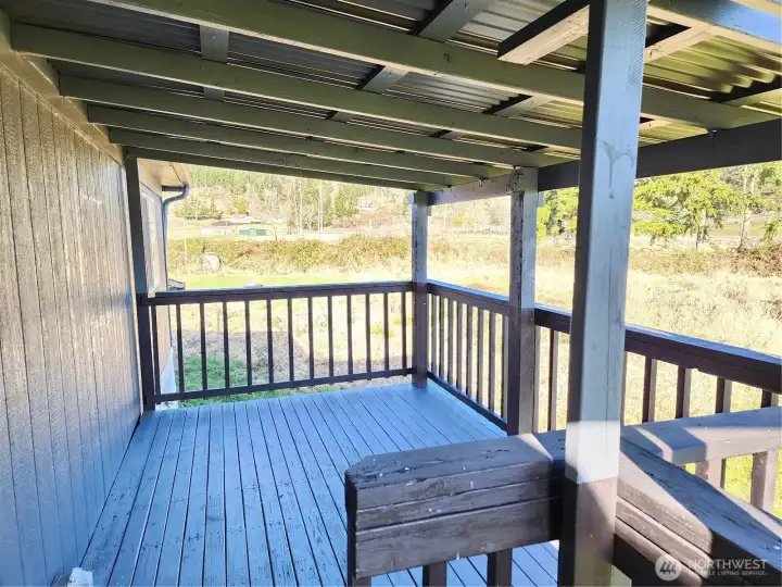 Covered rear deck—shown empty and with the large trees behind the house, nature out your back door.