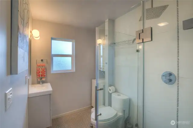 The second bathroom is compact, but makes exquisite use of space. The washer/dryer is in the far corner and the shower has penny tile that spans the flooring of the entire space.