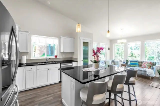 Large kitchen with granite counters, tile backsplash, stainless steel appliances, pantry, and breakfast island.