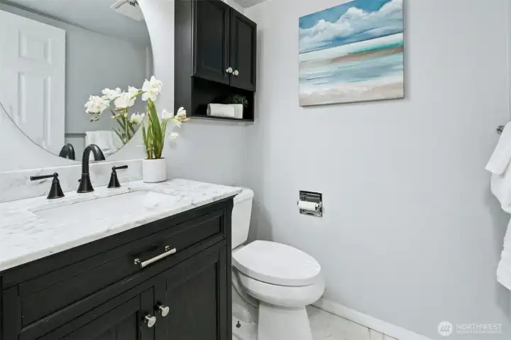Updated half bath with marble vanity and modern fixtures.