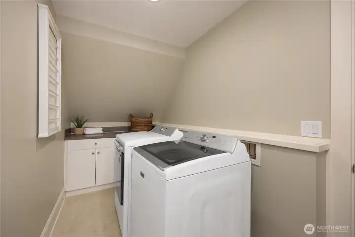 Convenient upper-level laundry room with storage and folding area.