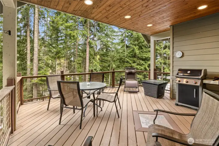 A generous covered deck extending from the dining space, perfect for gatherings, grilling, or simply enjoying the fresh outdoor setting in any season.