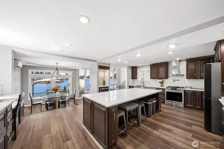 Custom-designed kitchen showcases a gas range with pot filler, a spacious island with beverage area, and a built-in desk, blending functionality and style for both cooking and everyday living.