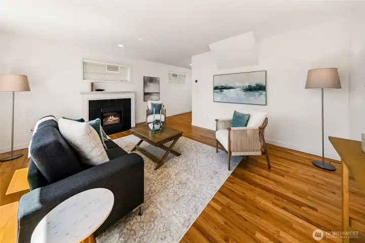 Bright living room with hardwoods, fireplace and generous windows.