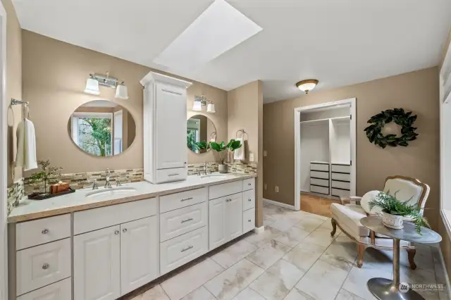 The primary bathroom has been recently updated with white cabinetry, quartz countertops, tile backsplash, tile flooring, and a beautiful freestanding soaking tub.