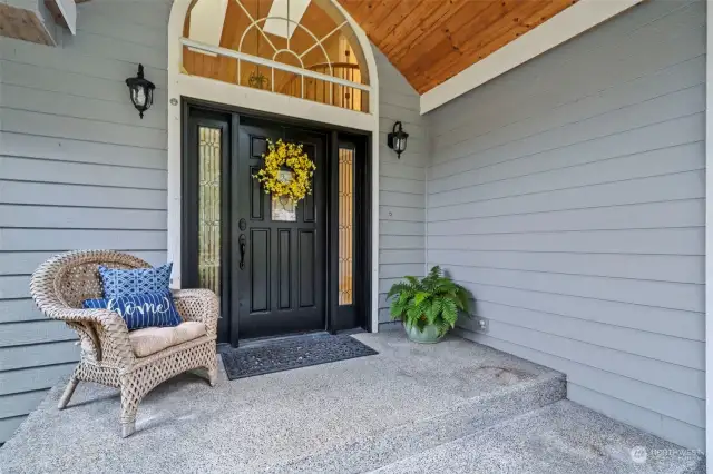 A welcoming covered front porch with arched window greets guests as they arrive.