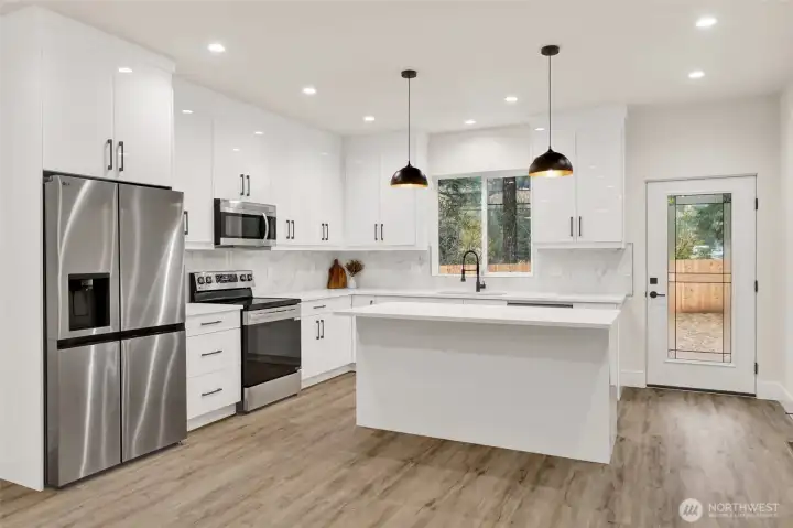 Sparkling kitchen complete with SS appliances, soft close cabinetry, quartz counter-tops, and eat in center island, great for entertaining. Door Leading to Covered Back Patio...