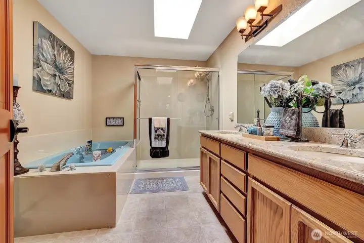 Primary bath with double vanity featuring granite countertops, large soaking tub and walk-in-shower