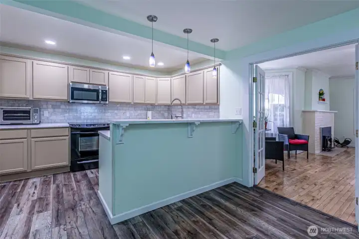 Kitchen view to the living room with French doors open.   Laminate floors in the kitchen, dining, mudroom & utility rooms.