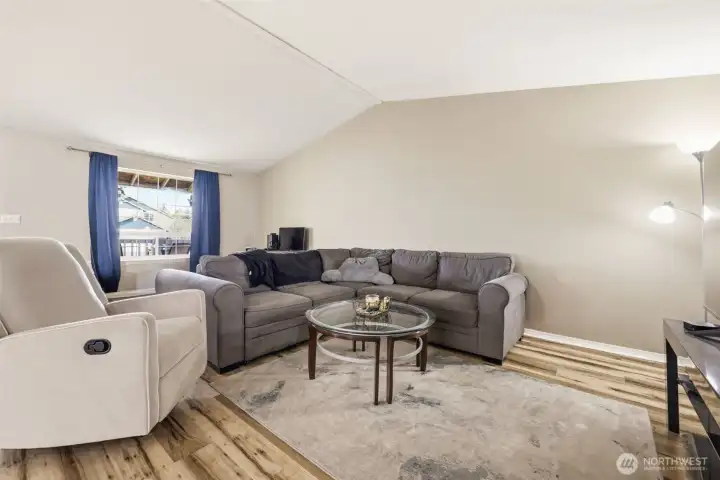 Large open-concept living room, kitchen, and dining area with vaulted ceilings that enhance the spacious feel and natural light.