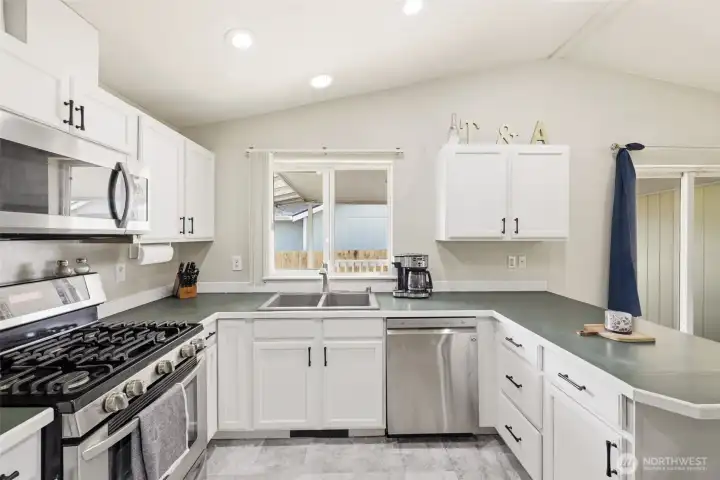 Light and bright kitchen featuring freshly painted cabinets with new hardware pulls, stainless steel appliances, gas stove, and microwave—offering a clean, updated look and great functionality for everyday cooking.
