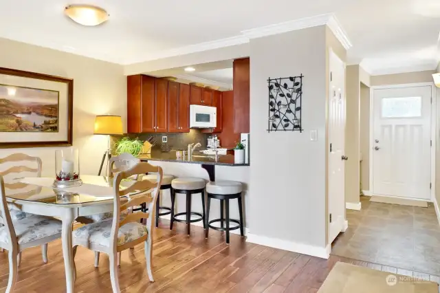 Dining area with kitchen eating bar for four, and open to the kitchen. the closet in entry is the stack washer and dryer.