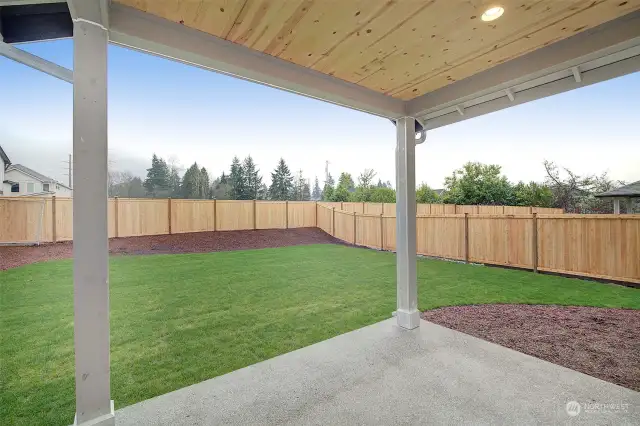 Lit covered patio overlooking a large yard.