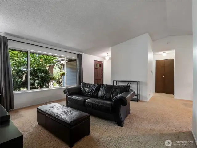 The living room is spacious with a massive window looking out to the front yard. Vaulted ceilings add to the expansiveness of this space.