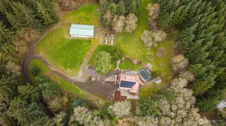 Birds eye view of 6 acre property with log home, detached garage, two story shop, outdoor pool, raised beds and so much more!