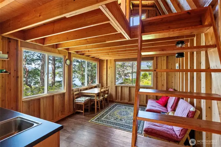 Main floor of the tiny home complete with kitchen sink, dining table, and futon couch. Stairs head up to the loft with more beds and that view!
