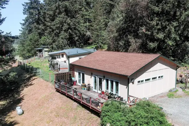 Bunkhouse has French doors to private deck. Main house has a metal roof and deck, with an enclosed sunroom that is heated and air conditioned. Main house has a fenced yard. Tiny Home/Studio shown past the main house.