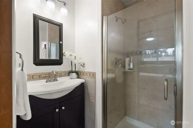 The glass shower doors opens up the space while highlighting the floor to ceiling tiling.