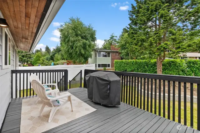 A deck off the kitchen is spacious and overlooks a beautiful backyard.