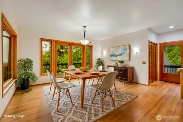 Large dining space surrounded by windows and two doors to access the expansive deck.