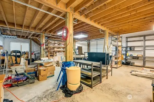 1,200 sqft lower level of the shop with tons of shelves and work benches and three garage doors that allow you to pull a vehicle all the way through.