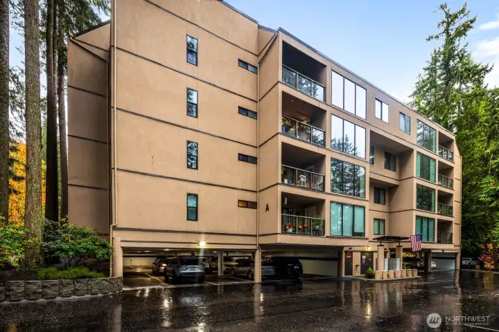 Building exterior showcasing large windows and covered balconies set against forest surroundings.