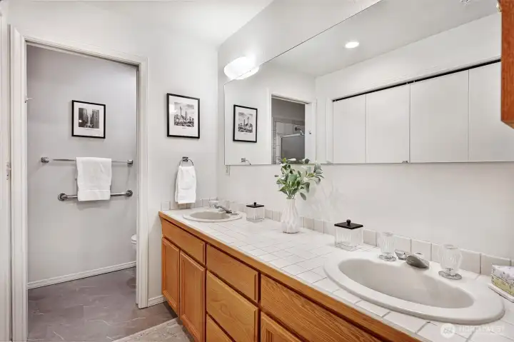 Primary bathroom with double sinks, updated flooring and second closet.