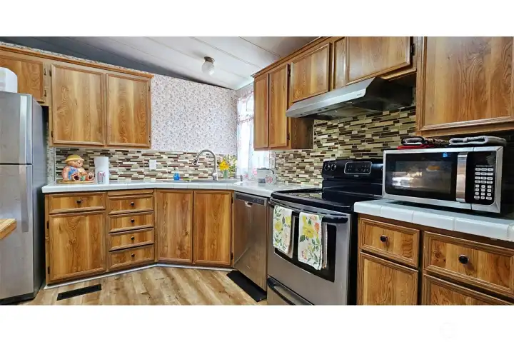Spacipuos Kitchen backsplash and stainles steel appliances. Dishwasher, Stove Microwave, Fridge