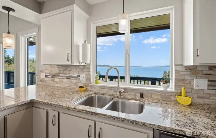 White kitchen with tile backsplash and pendant lighting.