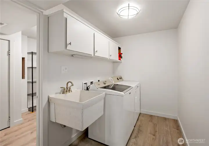 Laundry room with deep sink and storage cabinets.