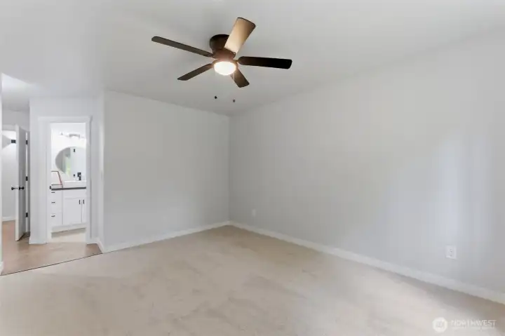 Bright, airy, and peaceful. The primary bedroom features plush new carpet, fresh paint, and a large window looking out toward the tranquil backyard greenery.
