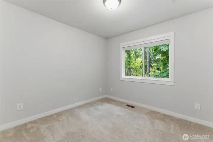 Another bright and comfortable bedroom! Featuring brand-new carpeting, fresh paint, and a large window that frames the tranquil, wooded views outside.