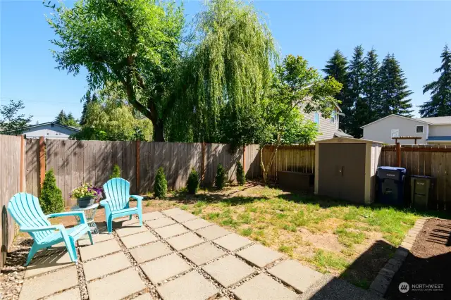 Fully fenced back yard with patio and storage shed.