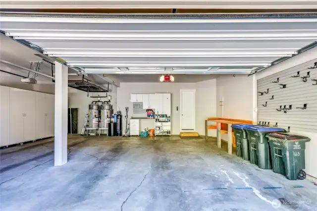 The over-sized, 3-car garage, houses two water heaters, a water treatment tank and an EV charging unit. Shelving comes with the home.