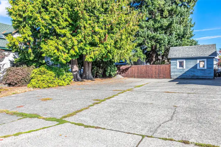 Paved parking area and blue shed are a part of the vacant lot.
