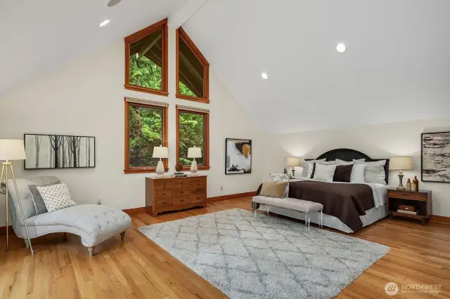 Generously proportioned space in this Primary Suite with Cathedral Ceilings, hardwood floors, walls of windows and views of the lush surroundings.