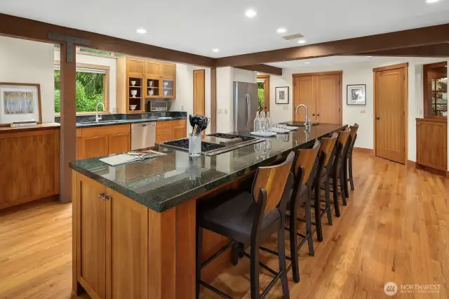 Kitchen has extra-long prep island with bar seating, 4-burner gas cooktop with grill