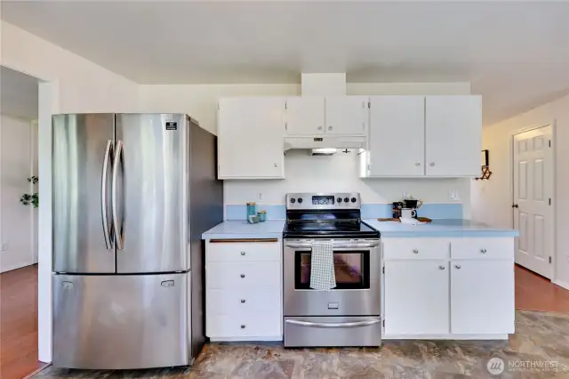 Kitchen features new flooring, freshly painted cabinets, and new cabinet hardware.