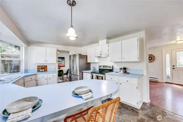 Kitchen with breakfast bar, looking towards living room and front entrance.