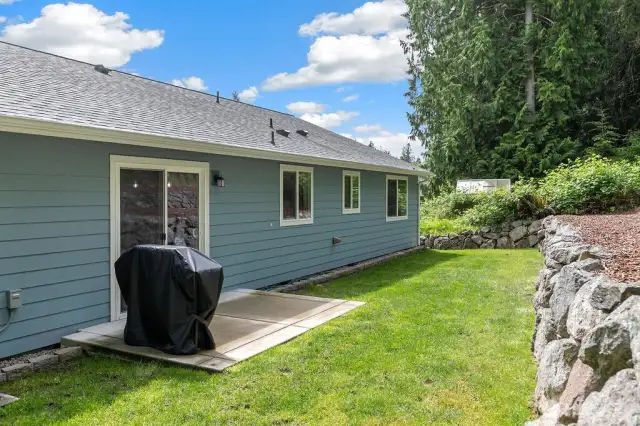 Backyard has poured concrete area, perfect for barbequing.