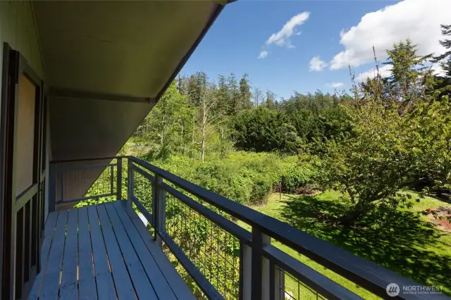 Upper deck off Primary bedroom overlooks landscaped front yard.
